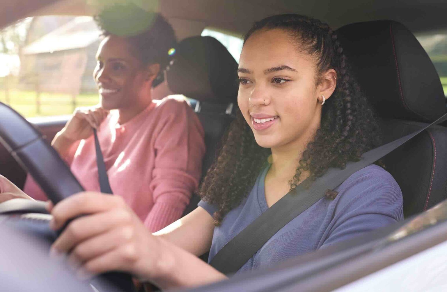 Teenage girl in drivers seat with parent riding in passenger seat | Daniel Stark Injury Lawyers