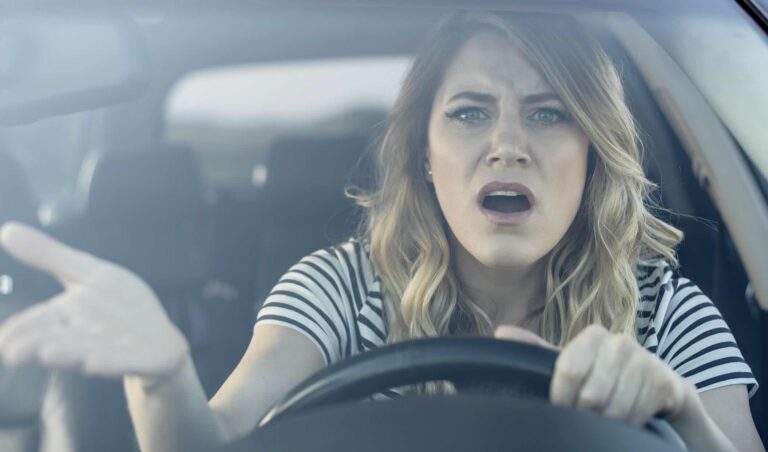 Woman in the driver's seat gesturing angrily toward another vehicle during a road rage incident | Daniel Stark Injury Lawyers