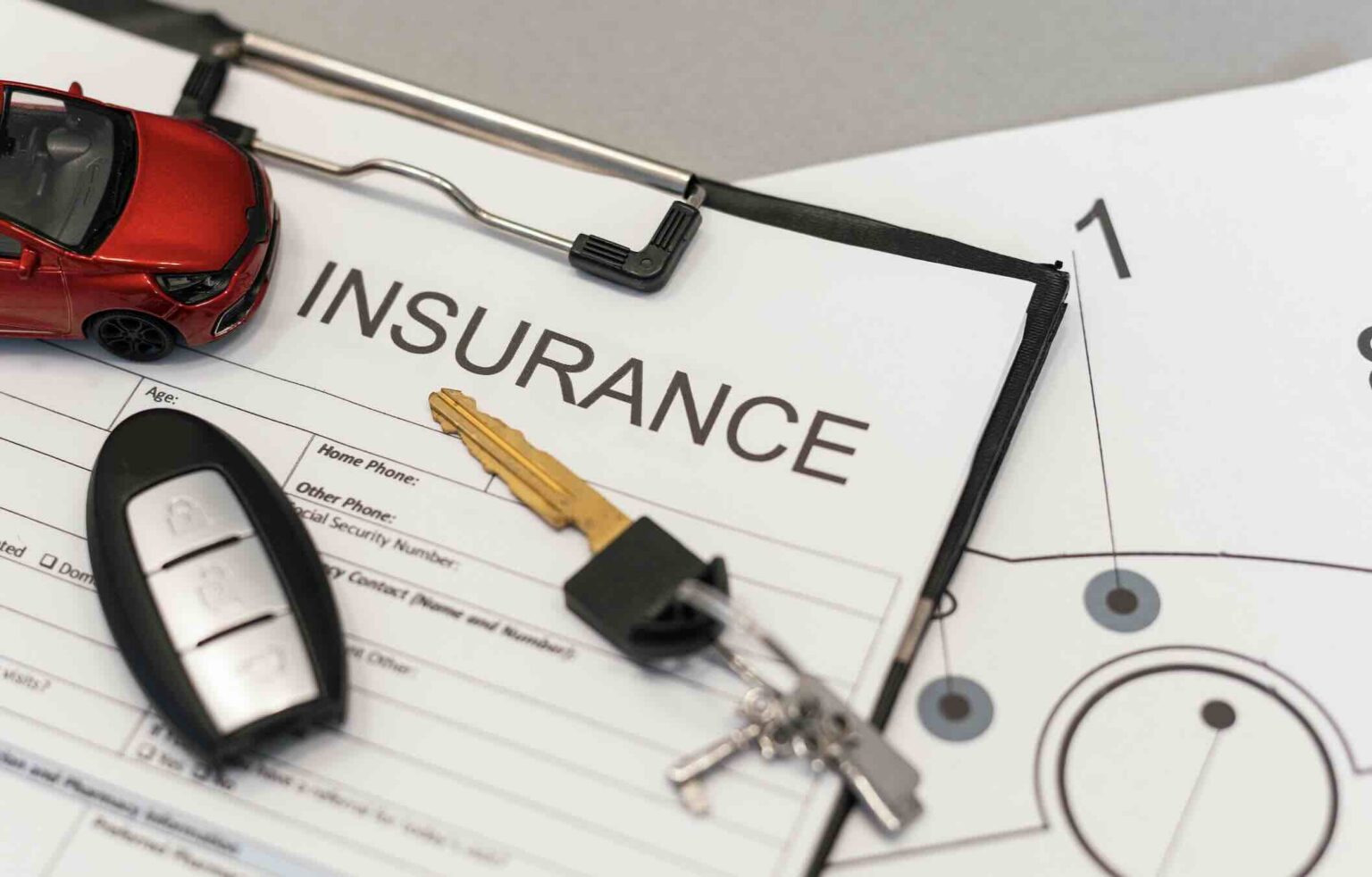 Insurance paperwork on a desk with keys and model car representing car insurance laws in Austin, Texas