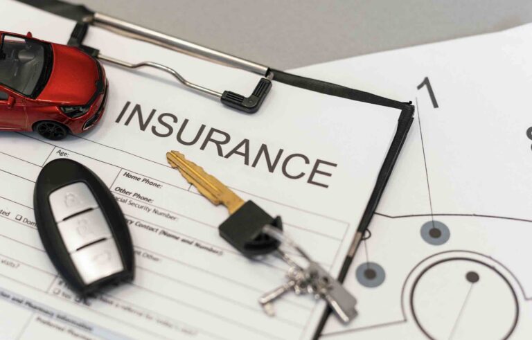 Insurance paperwork on a desk with keys and model car representing car insurance laws in Austin, Texas