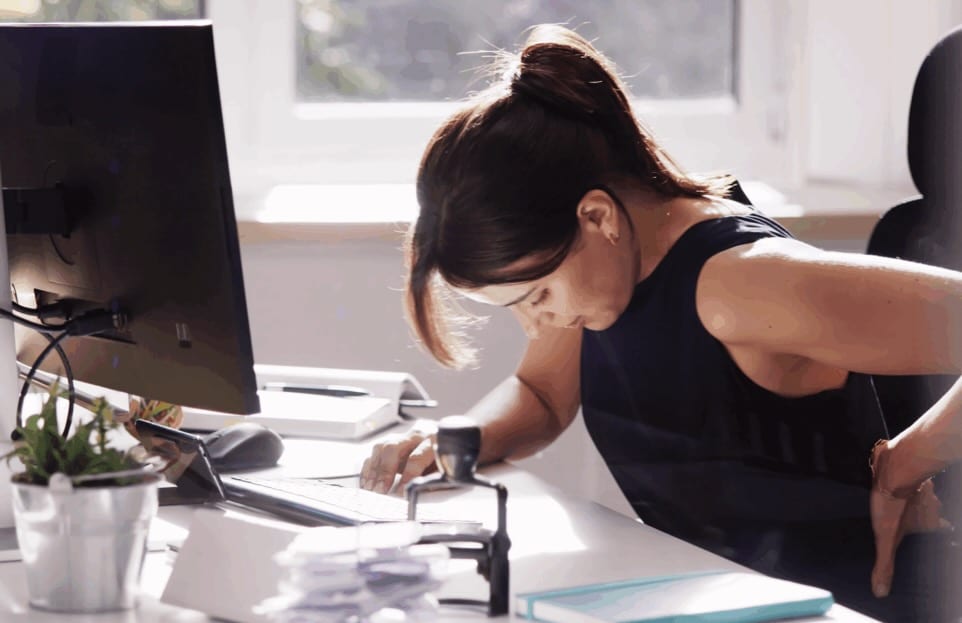 A woman at a desk suffering from a herniated disk | Daniel Stark Injury Lawyers