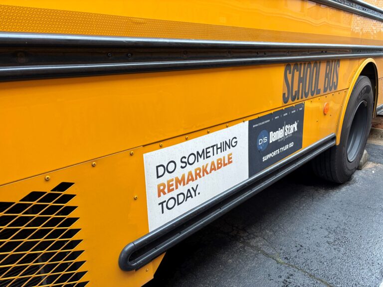 School bus with a sign for the Do Something Remarkable safety campaign run by Daniel Stark Personal Injury Law Firm.