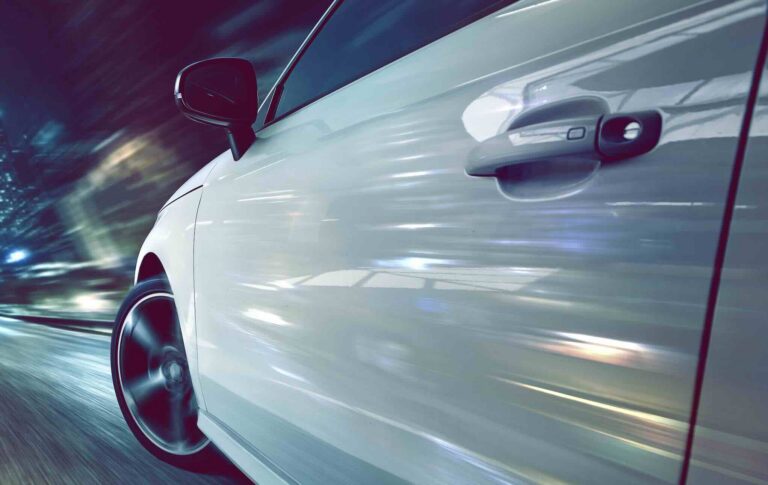 Exterior view of a white car driving on a highway, illustrating highway hypnosis and road safety | Daniel Stark Injury Lawyers