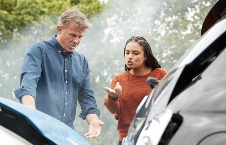 A man and woman arguing in front of the scene of a car accident trying to figure out fault | Daniel Stark Injury Lawyers