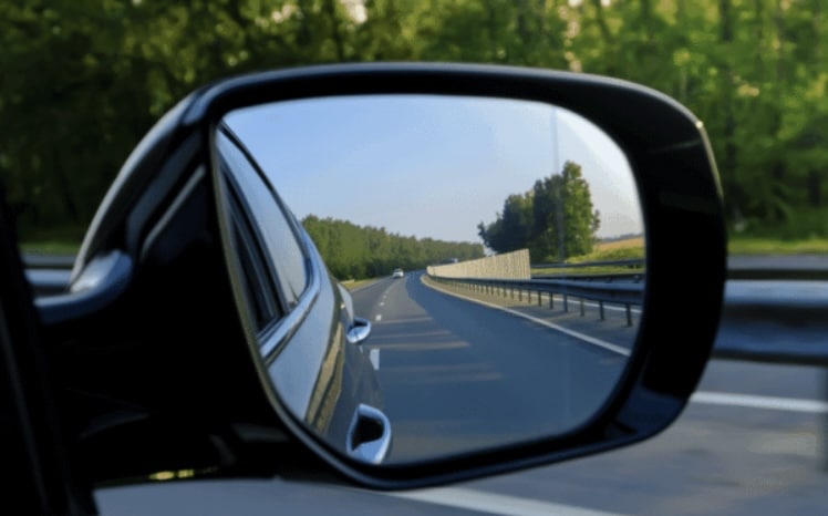 Photo of a car side mirror with a car behind in the reflection | Daniel Stark Injury Lawyers