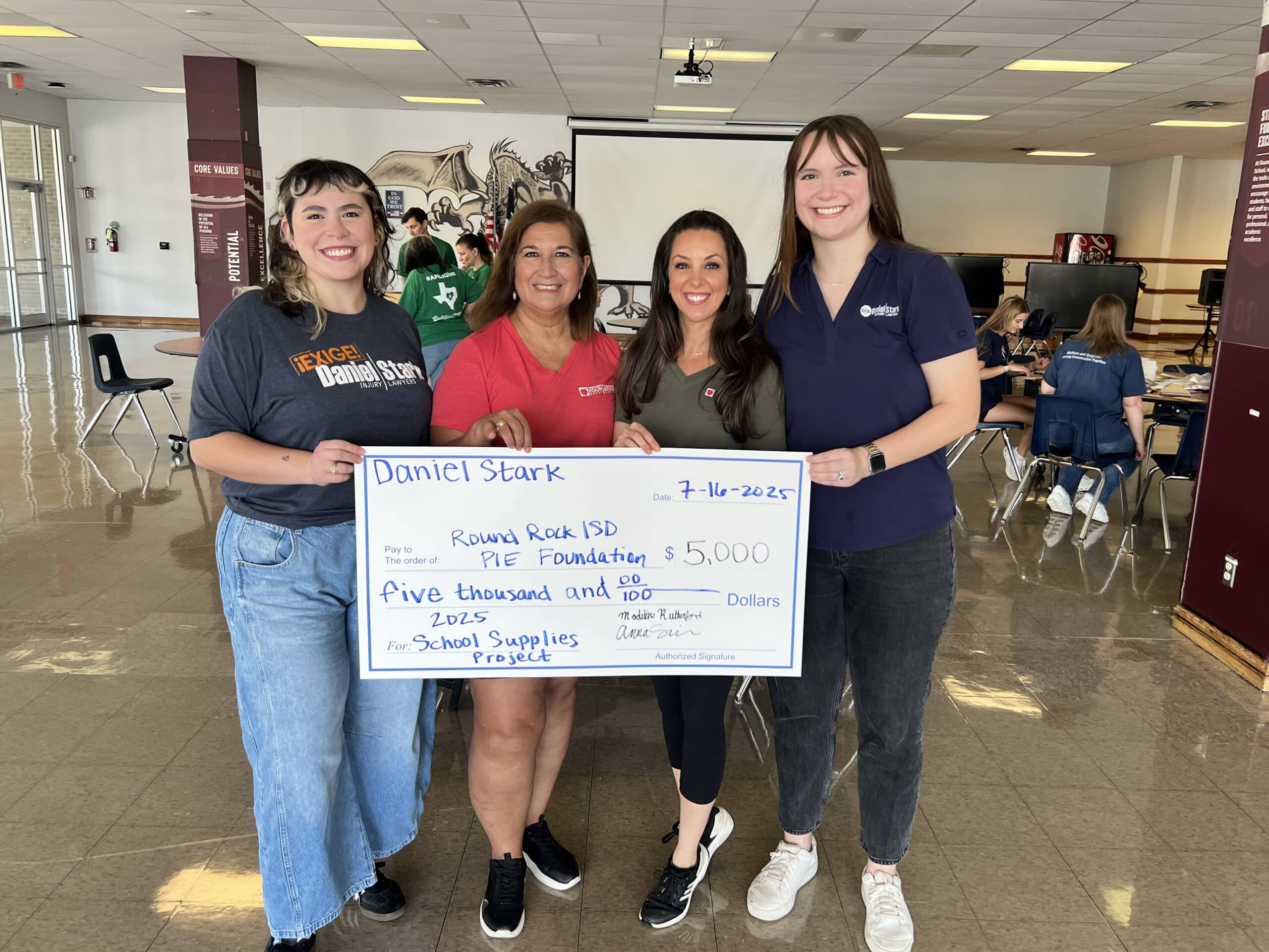 Four women holding a giant cheque from Daniel Stark Injury Lawyers, with a written donation of ,000 to Round Rock ISD Project School Supply to support local students and teachers in 2025 | Daniel Stark Law