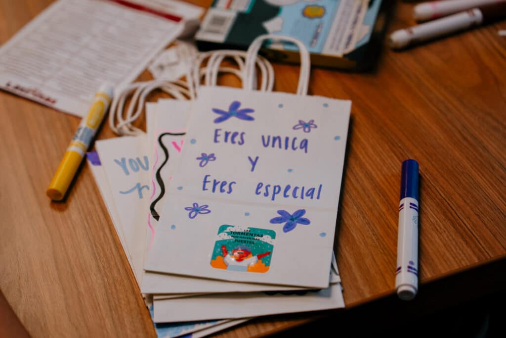 Close-up of handmade snack bags with encouraging Spanish messages for Latinitas summer campers, surrounded by markers and supplies | Daniel Stark Law