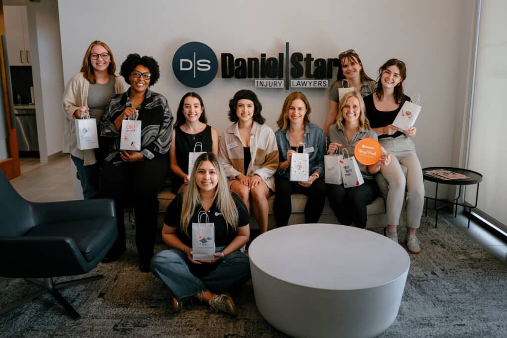 Daniel Stark Injury Lawyers team members smiling and holding decorated snack packs prepared for Camp Latinitas participants | Daniel Stark Law