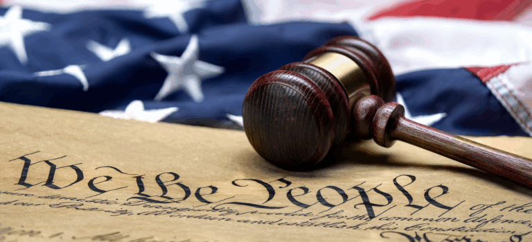 Close-up photo of the U.S. Constitution Preamble with a judge’s gavel resting on top of an American flag, symbolizing justice, law, and civil rights in the United States | Daniel Stark Law