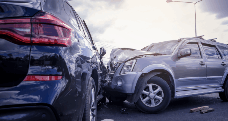 Low-angle photo showing collision impact between a silver car and a black car | Daniel Stark Injury Lawyers