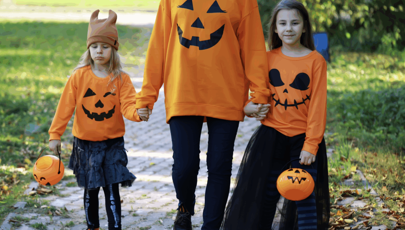 Mom and kids trick-or-treating safely on the sidewalk with candy buckets and festive costumes | Daniel Stark Injury Lawyers