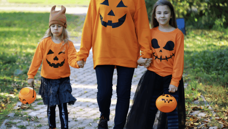 Mom and kids trick-or-treating safely on the sidewalk with candy buckets and festive costumes | Daniel Stark Injury Lawyers
