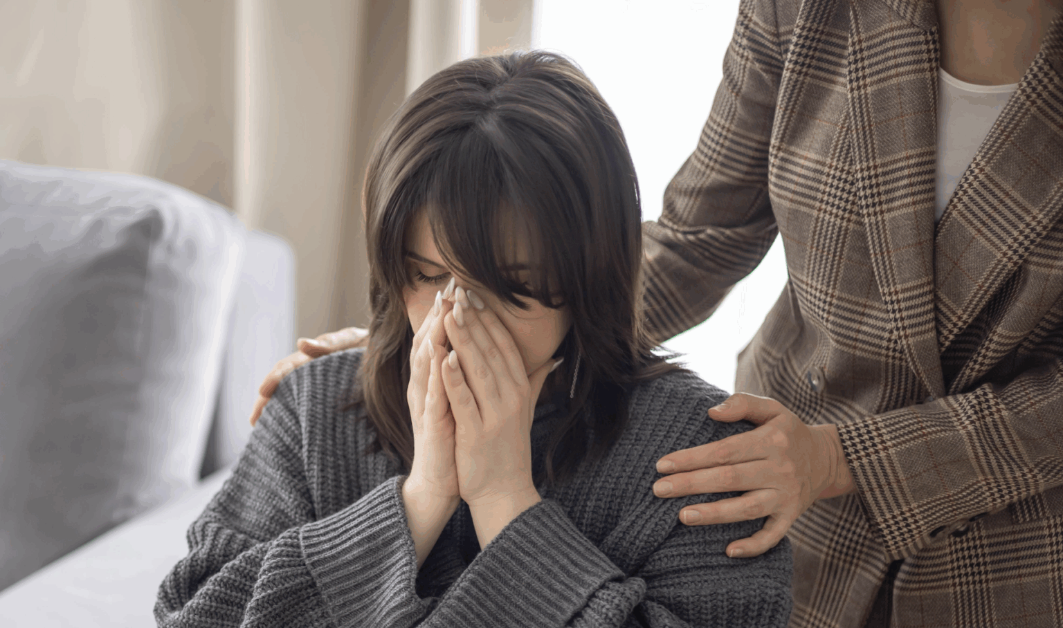 A woman sits with her face in her hands as her attorney offers support during a legal consultation in a Texas law office | Daniel Stark Injury Lawyers