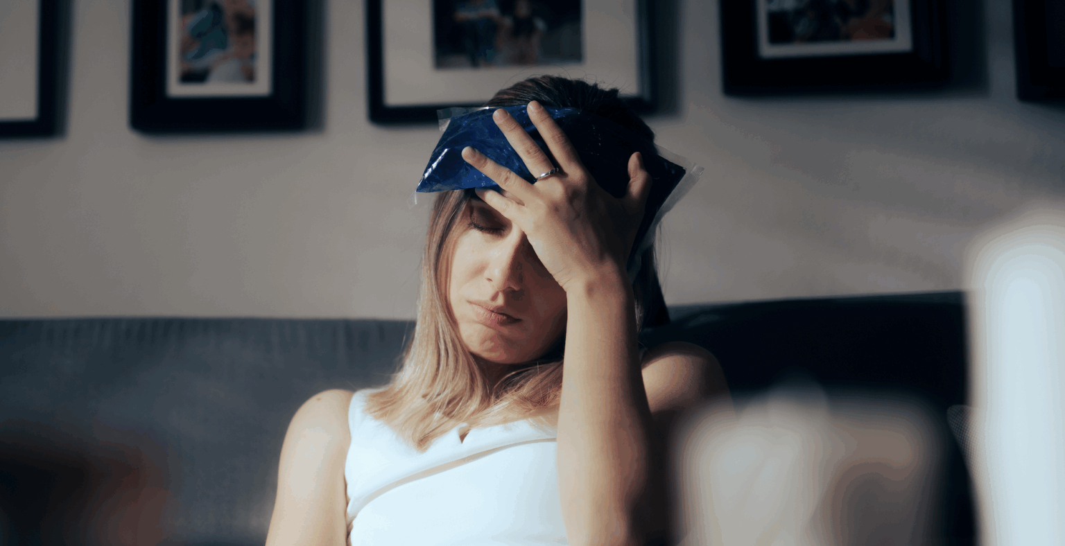 Woman sitting on couch with ice pack on head, looking distressed | Daniel Stark Injury Lawyers