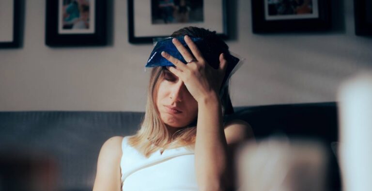 Woman sitting on couch with ice pack on head, looking distressed | Daniel Stark Injury Lawyers