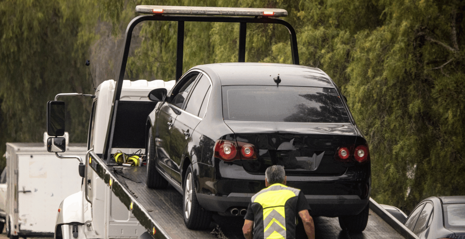 Tow truck lifting black vehicle at accident scene | Daniel Stark Injury Lawyers
