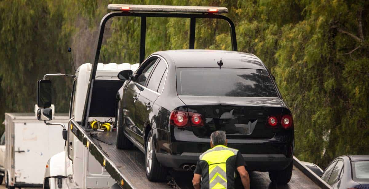 Tow truck lifting black vehicle at accident scene | Daniel Stark Injury Lawyers