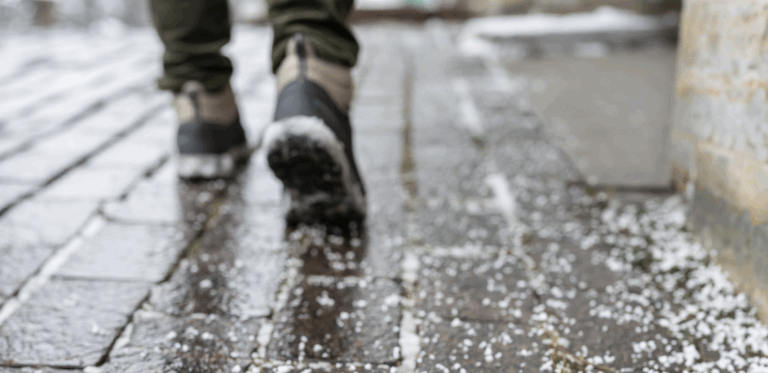 Boots stepping cautiously on a frozen sidewalk surface | Daniel Stark Injury Lawyers
