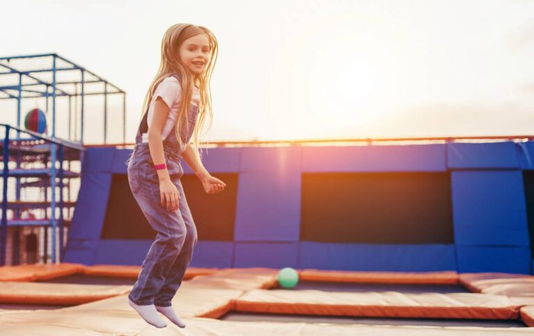 Young girl jumping on a trampoline at an outdoor recreation park | Daniel Stark Injury Lawyers