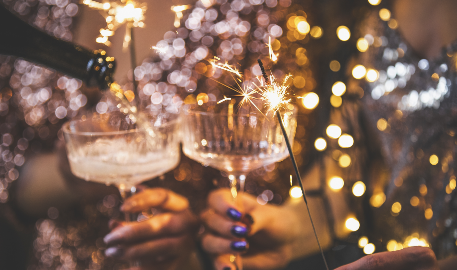 Woman pouring champagne into a glass as she celebrates New Year’s Eve with a sparkler | Daniel Stark Injury Lawyers