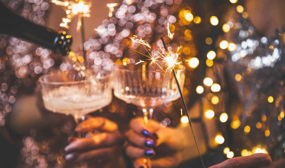 Woman pouring champagne into a glass as she celebrates New Year’s Eve with a sparkler | Daniel Stark Injury Lawyers
