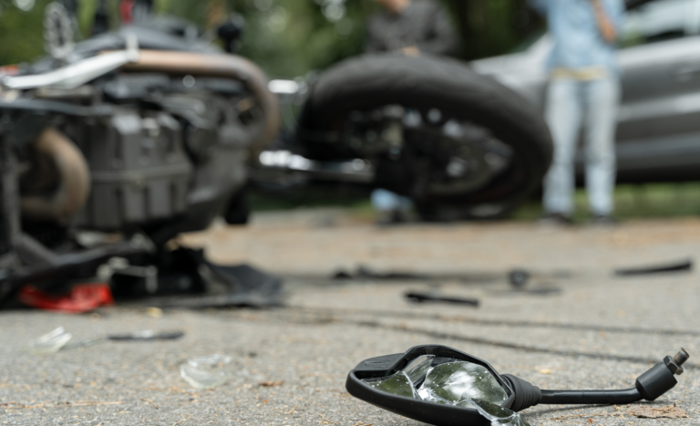 Debris scattered across the roadway after a motorcycle accident, with vehicles blurred in the background | Daniel Stark Injury Lawyers