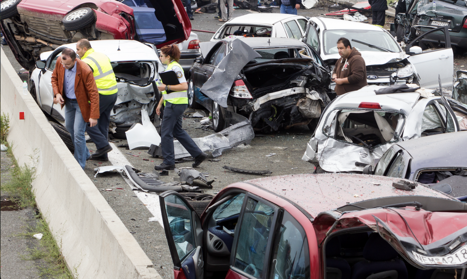 Aftermath of a multi-vehicle car accident on a roadway with damaged cars and people cleaning up debris | Daniel Stark Injury Lawyers