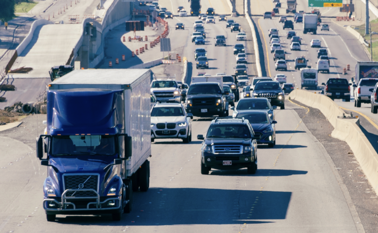 An 18-wheeler drives alongside passenger cars through traffic and construction on an Austin roadway | Daniel Stark Injury Lawyers