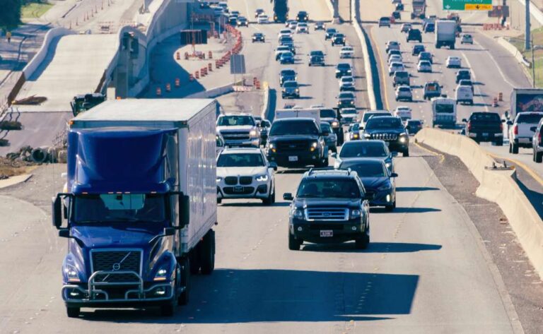 An 18-wheeler drives alongside passenger cars through traffic and construction on an Austin roadway | Daniel Stark Injury Lawyers