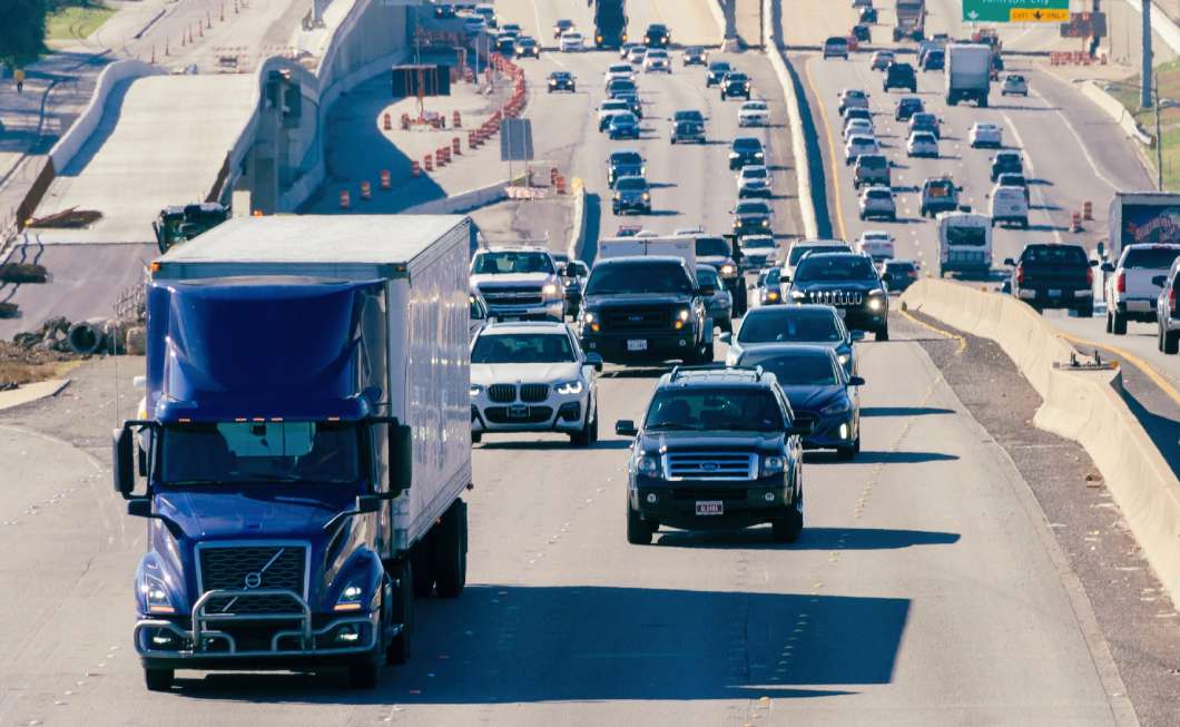 An 18-wheeler drives alongside passenger cars through traffic and construction on an Austin roadway | Daniel Stark Injury Lawyers