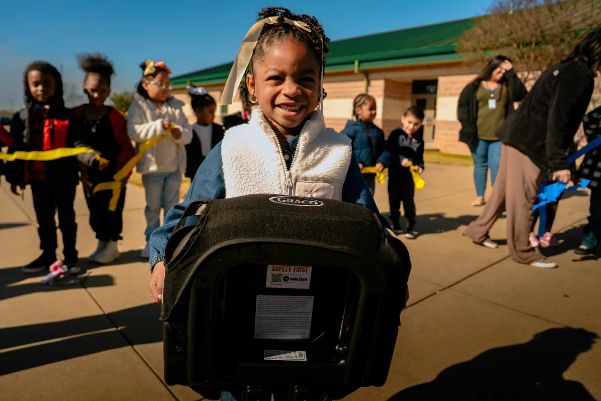 Young female student holding a booster seat at Waco event | Daniel Stark Injury Lawyers