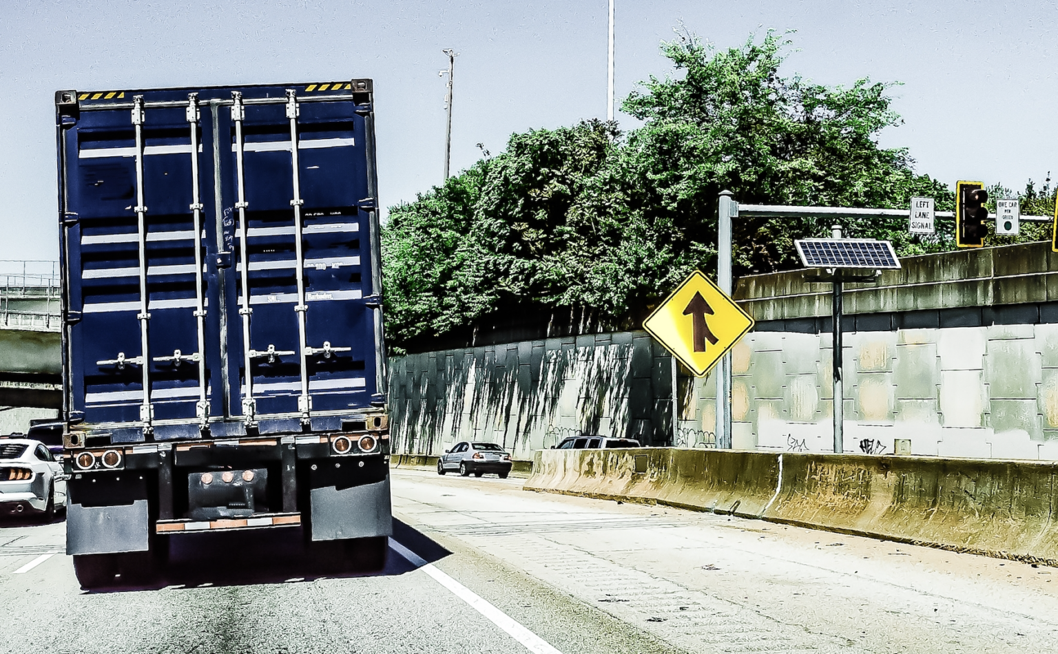 Small sedan merging onto a busy highway in front of a semi-truck during heavy traffic | Daniel Stark Injury Lawyers