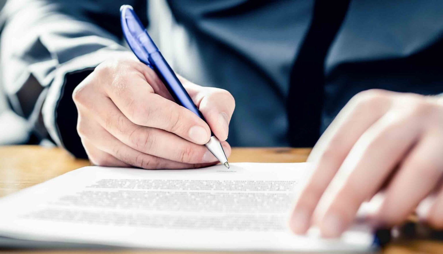 Person preparing to sign a car accident settlement document | Daniel Stark Injury Lawyers