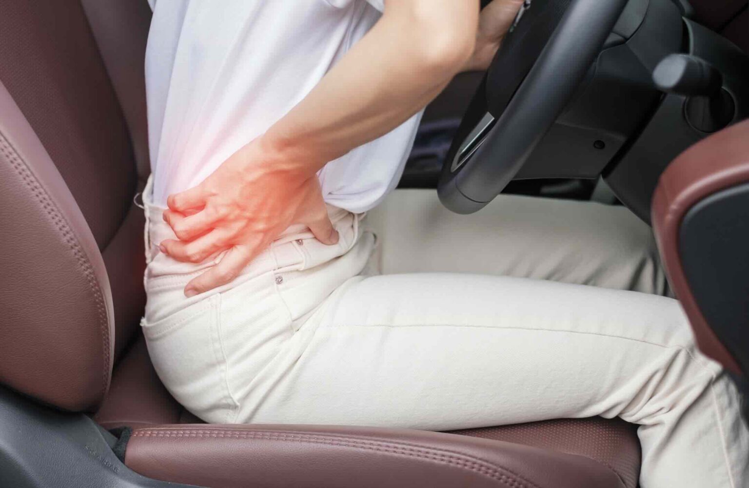 Woman grasping her lower back in car seat showing spine pain after car accident | Daniel Stark Injury Lawyers