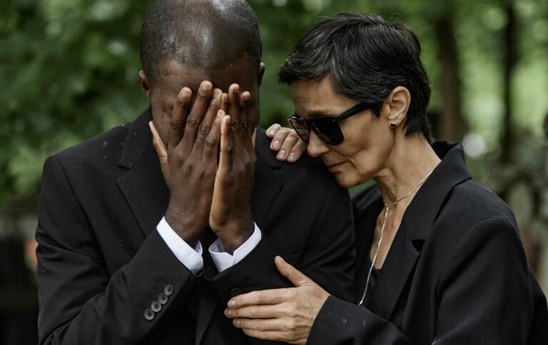 Family member consoling grieving man at funeral service | Daniel Stark Injury Lawyers