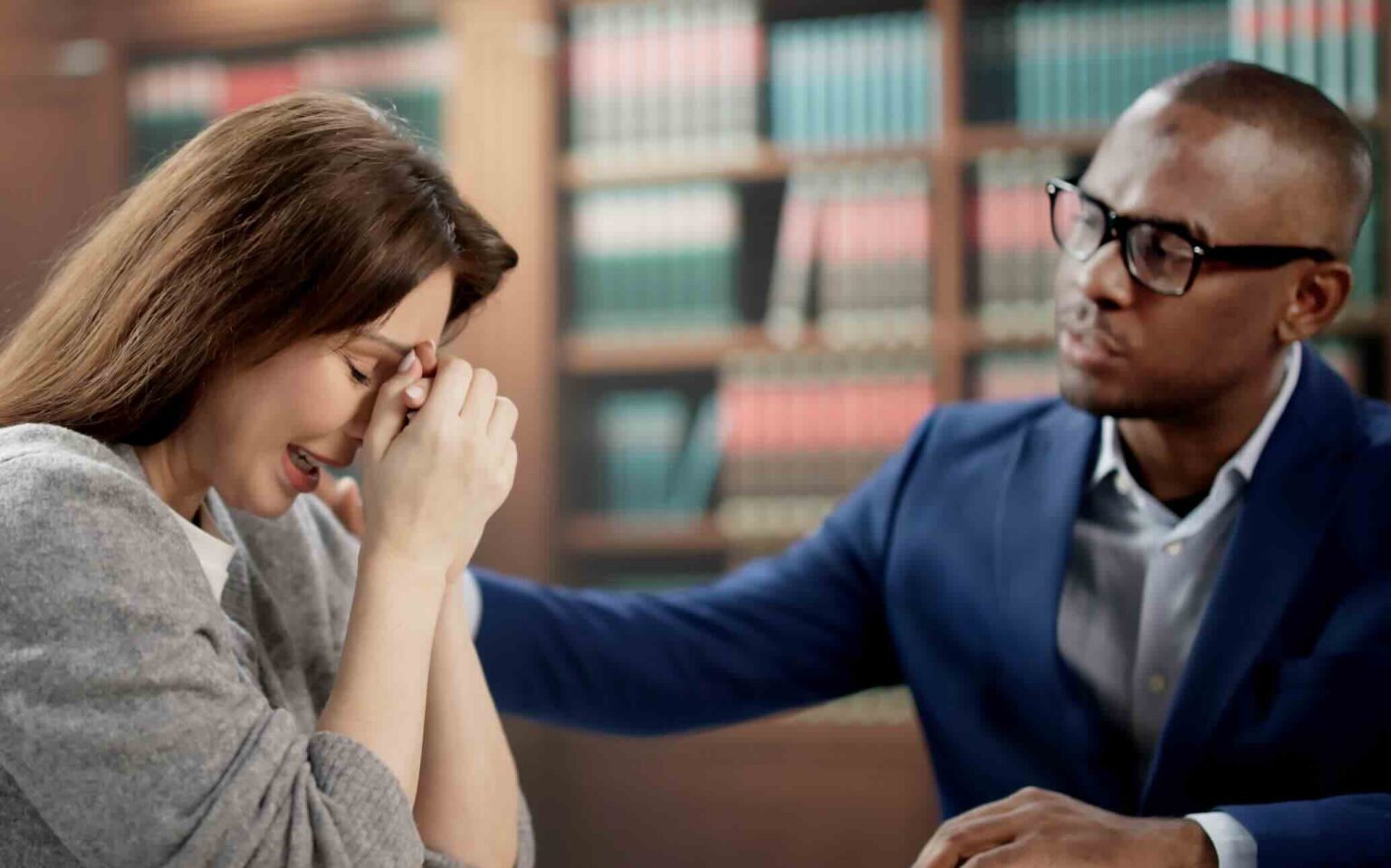Young woman crying into her hands while meeting with a wrongful death attorney in an office | Daniel Stark Injury Lawyers