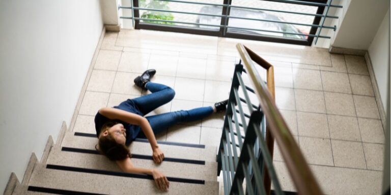 Young woman at the bottom of stairs after a slip and fall at apartment complex | Daniel Stark Injury Lawyers