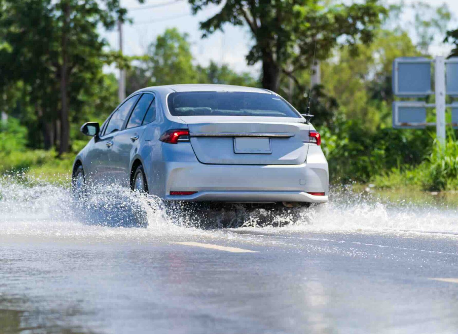 Silver car traveling through floodwater on a Texas road | Daniel Stark Injury Lawyers