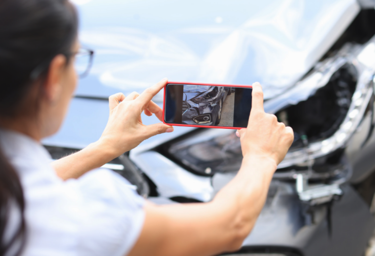 Young woman taking photos of wrecked vehicle after car accident | Daniel Stark Injury Lawyers